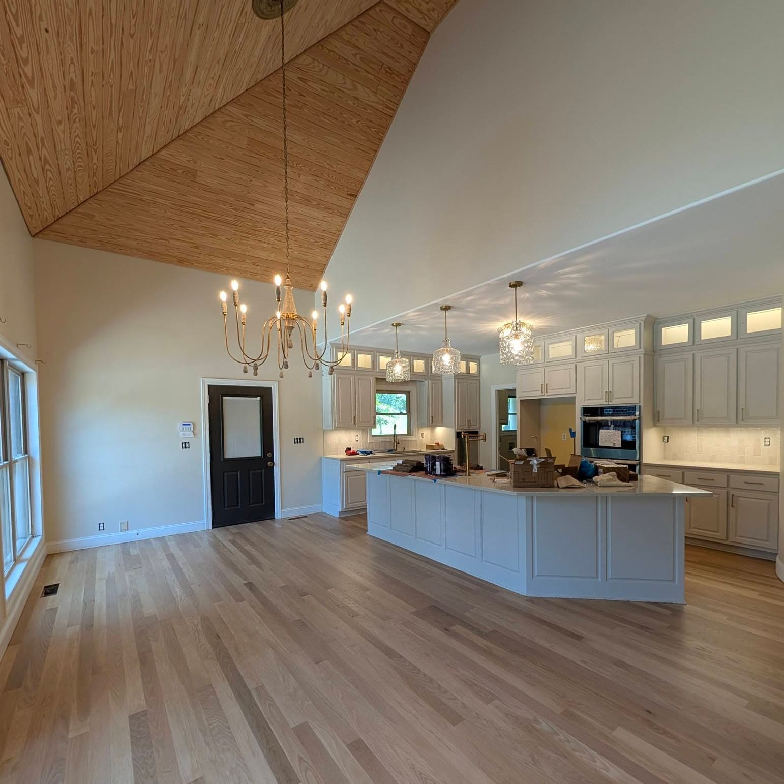 Light hardwood floors in an open kitchen and great room with a vaulted wood ceiling, a job by Alabama Hardwood Restoration