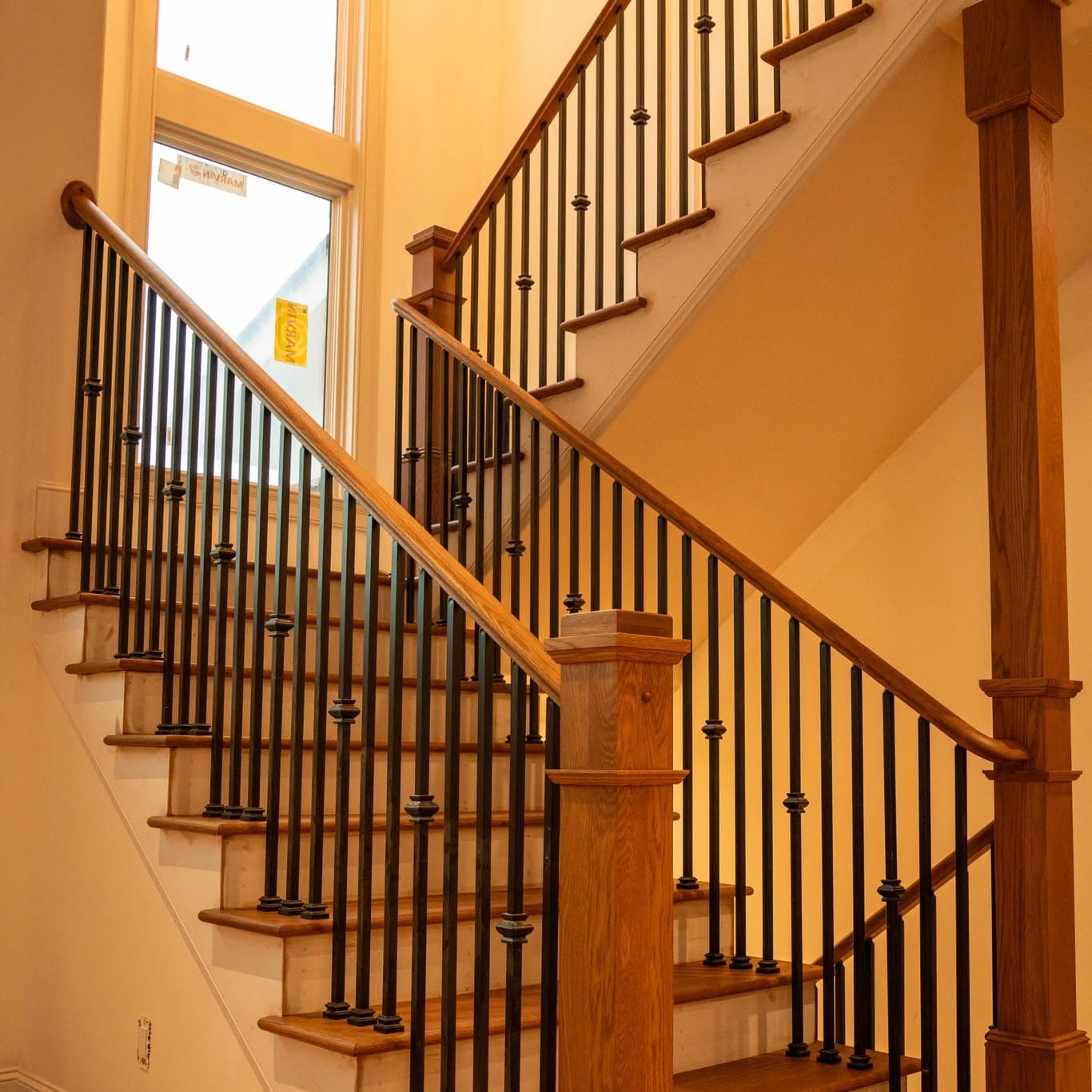 Hardwood staircase with oak treads, white risers, and black iron balusters, a job by Alabama Hardwood Restoration