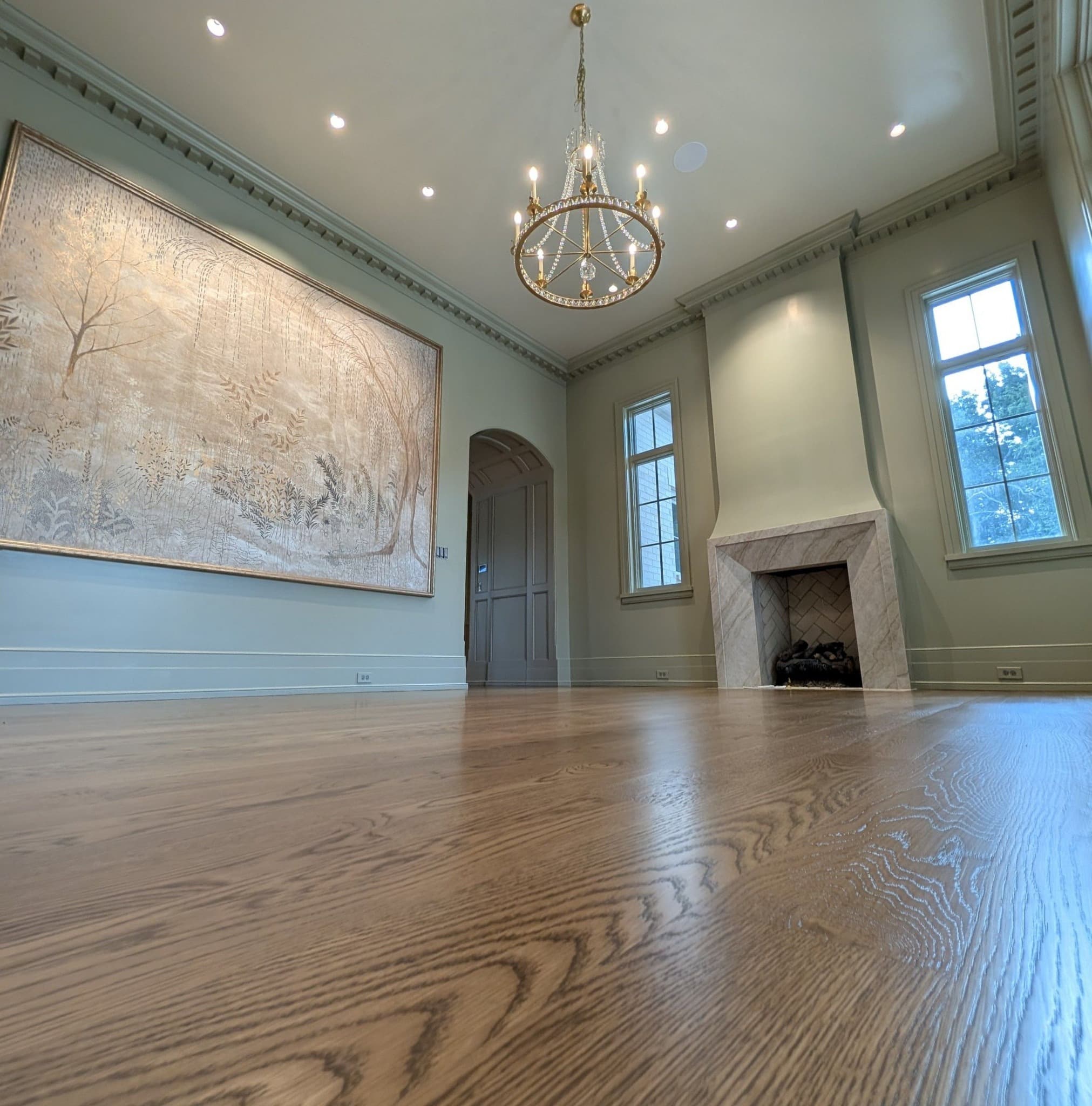 Wide-plank oak hardwood floor in a sage-walled living room with a marble fireplace, a job by Alabama Hardwood Restoration